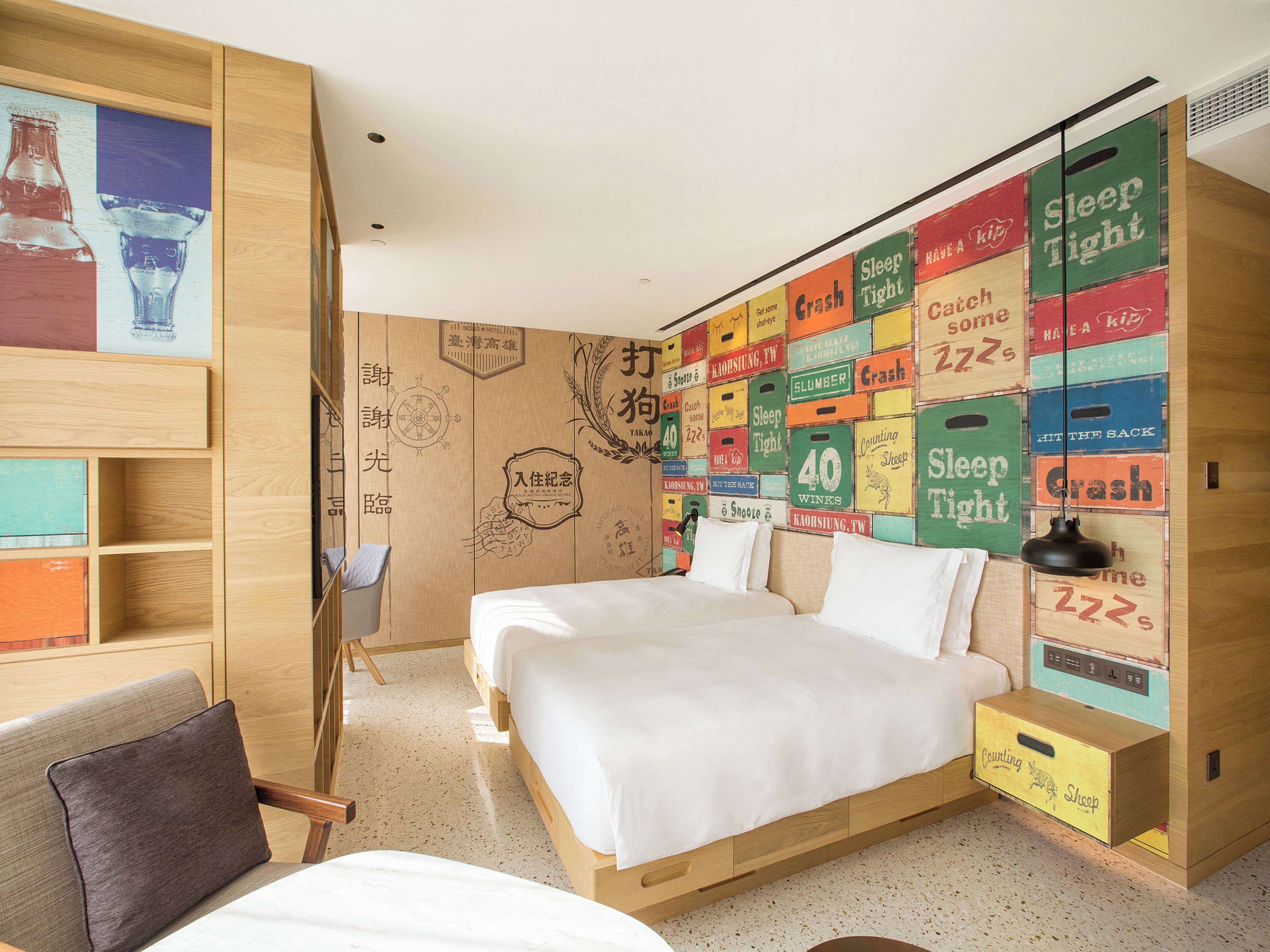 A bedroom with a bed, a chair, and a wall decorated with vintage-style signs.