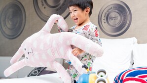 A child playing with a stuffed toy in a room with a bed, pillows, and a wall with circular designs. - Hotel Indigo Kaohsiung Central Park by IHG (Kaohsiung)