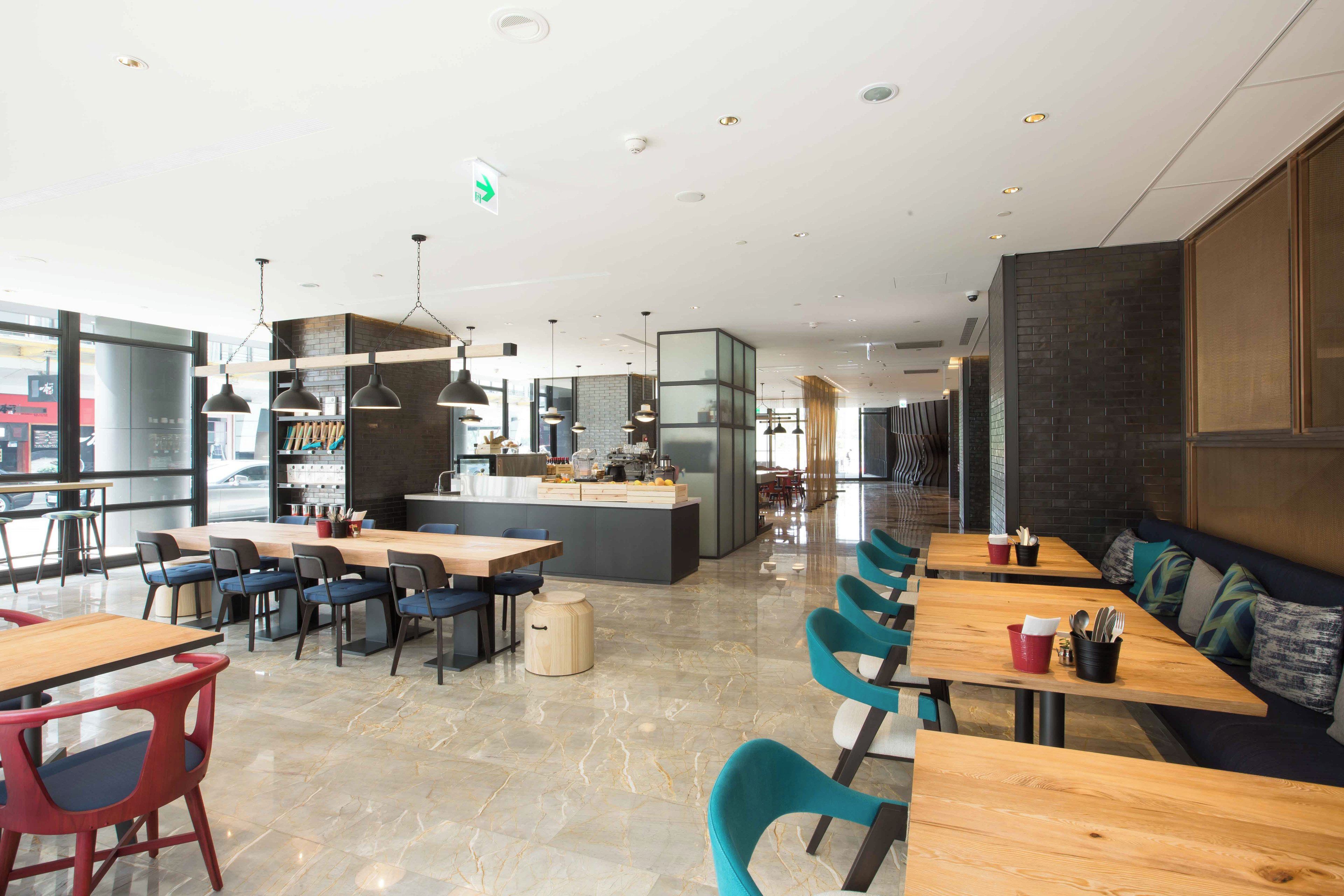 Een modern restaurant met een bar in het midden, zitmogelijkheden en een keuken op de achtergrond.