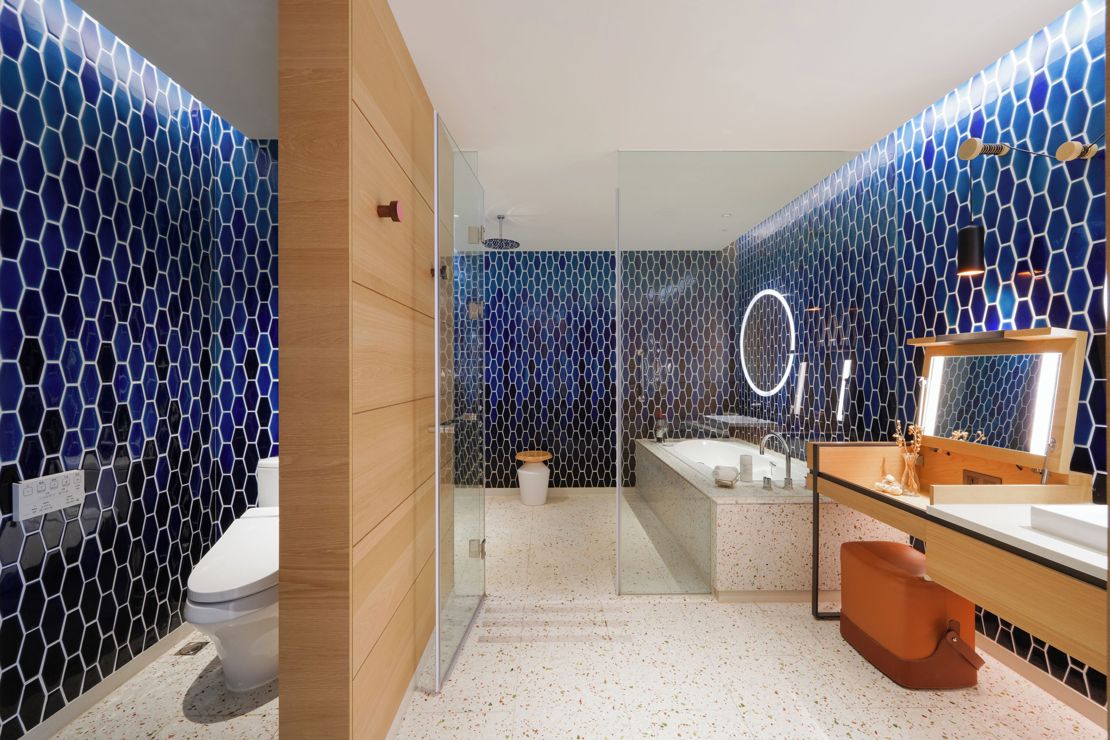 Un baño moderno con cabina de ducha de vidrio, una bañera blanca y un lavamanos con espejo.