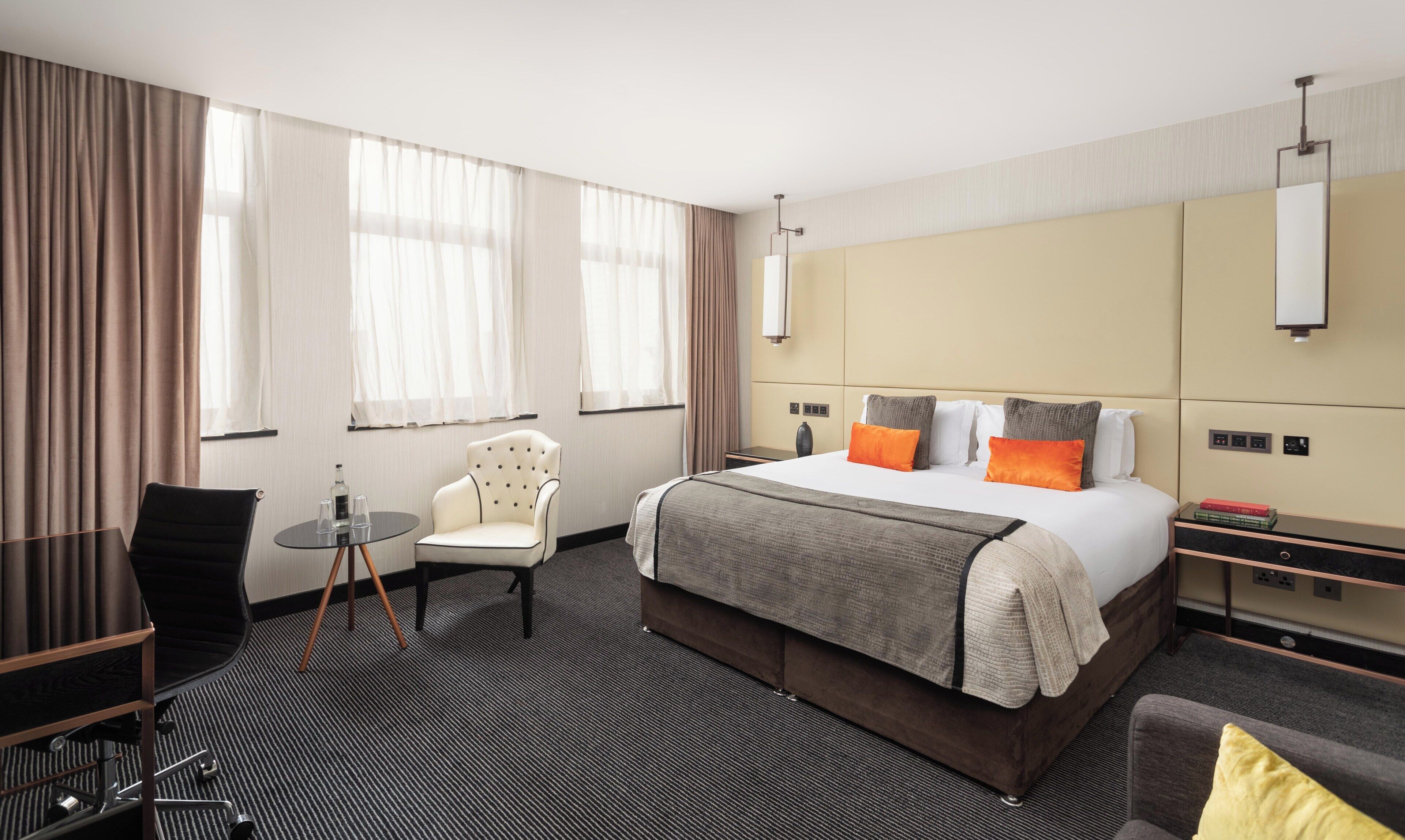 Habitación de hotel con una cama grande, un escritorio, una silla y una mesita.