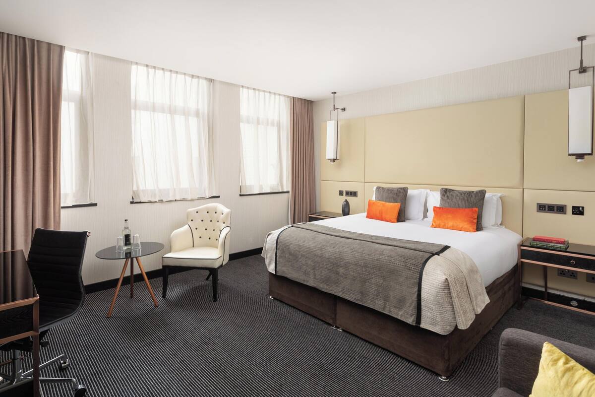 Habitación de hotel con una cama grande, un escritorio, una silla y una mesita.