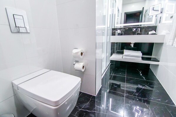 Een moderne badkamer met toilet, toiletrolhouder en een douchecabine van glas.