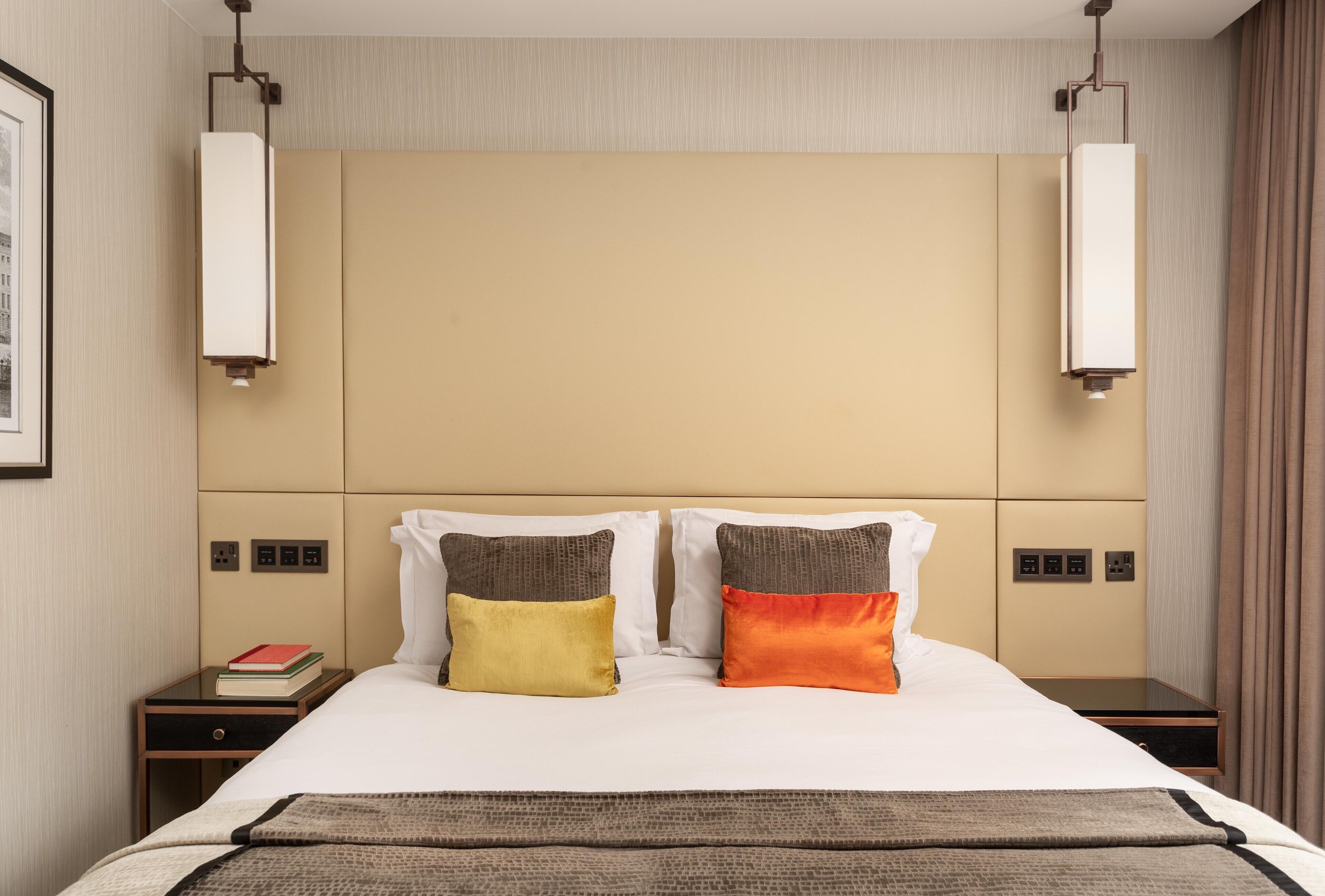 Una habitación de hotel con una cama grande, dos mesitas de noche y un cabecero con iluminación integrada.