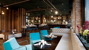 A modern restaurant with a bar area, seating arrangements, and a visible kitchen. - Montcalm Royal London House, Autograph Collection (London)