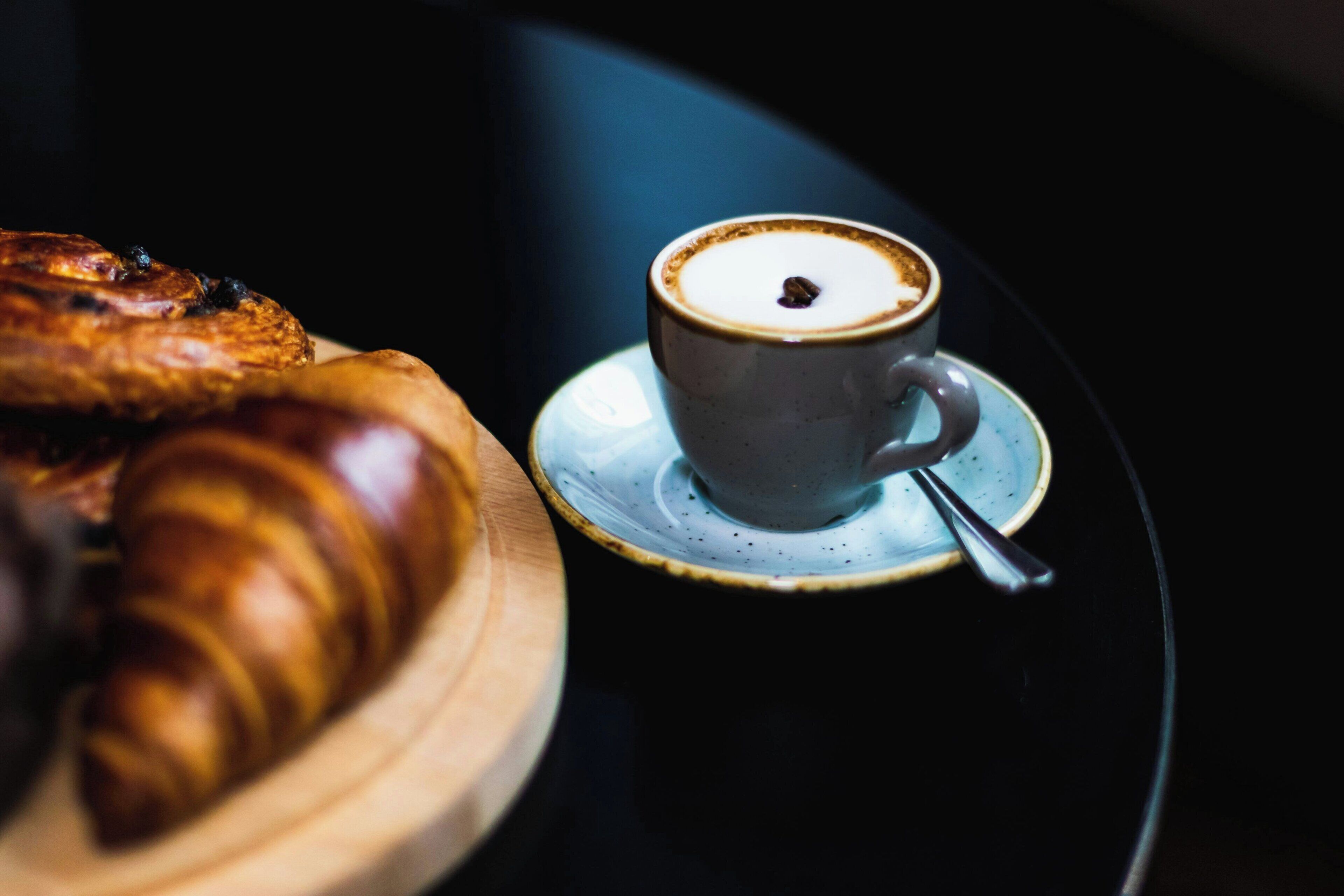 A croissant and a cup of coffee on a plate.