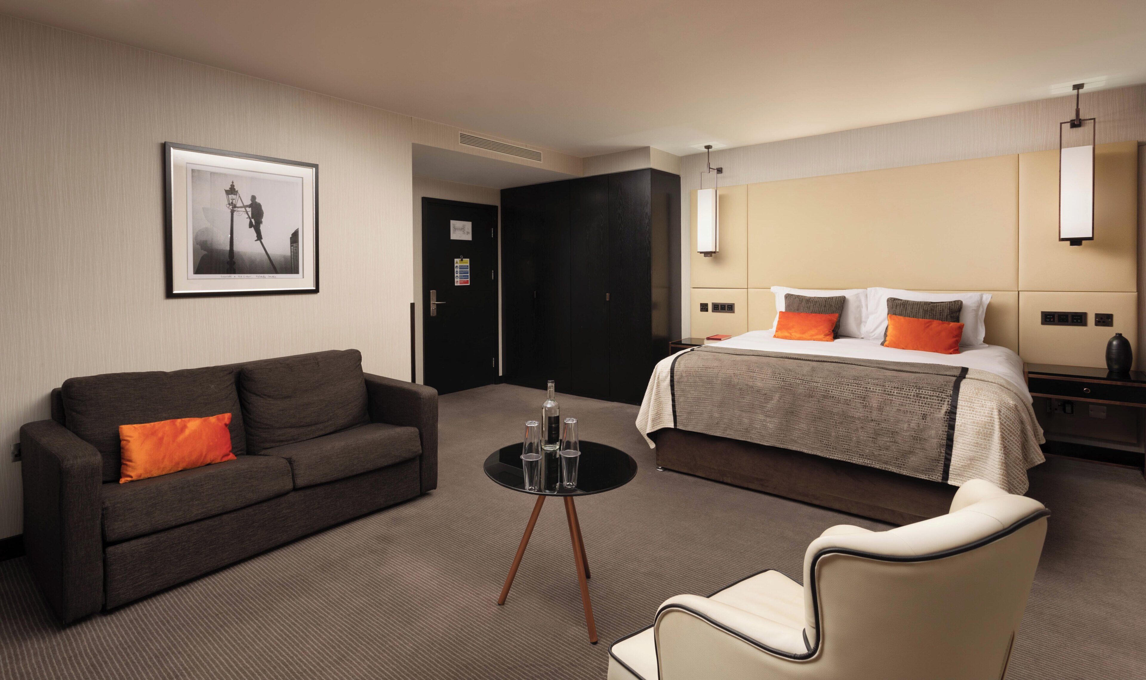 Una habitación de hotel con una cama, un sofá, una mesita con vasos y una silla.