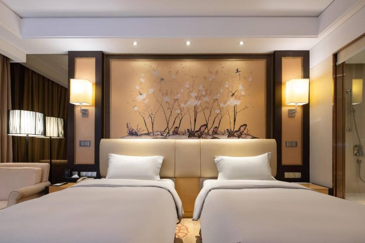 Een hotelkamer met twee bedden, een groot muurdecor en een douchegedeelte.
