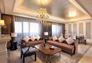 Ein luxuriöses Hotelzimmer mit einem großen Chandelier, bequemen Sofas, einem Glastisch und einem klassischen Essbereich.