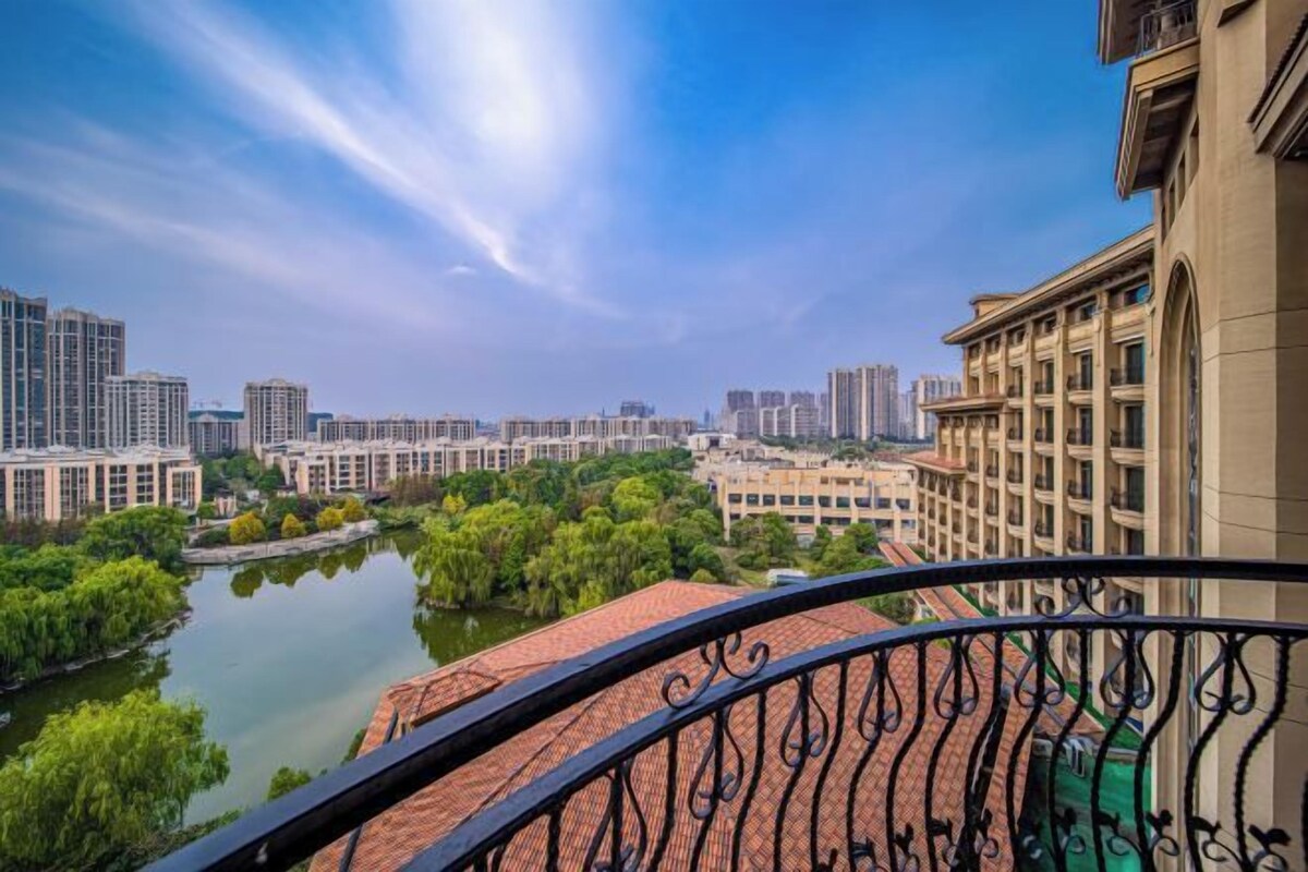 Un balcon offrant une vue sur le paysage urbain, avec des gratte-ciel et une étendue d’eau.