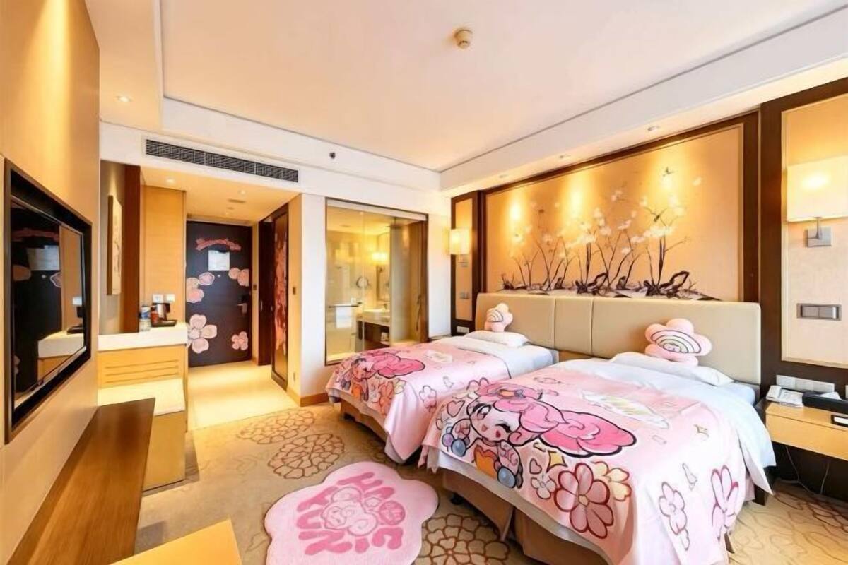 Een hotelkamer met twee bedden, een zithoek, een spiegel en een decoratieve wand.