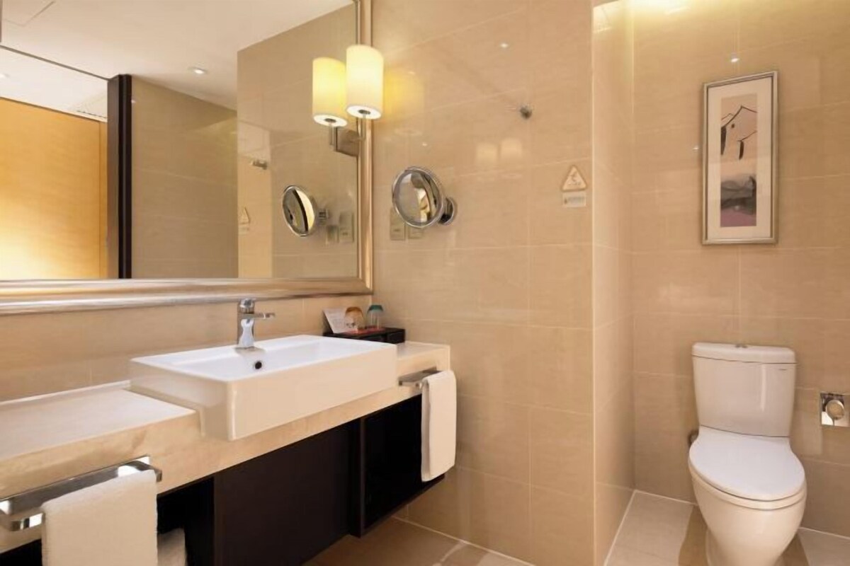 Une salle de bain moderne avec un double vasque, des toilettes et un grand miroir.