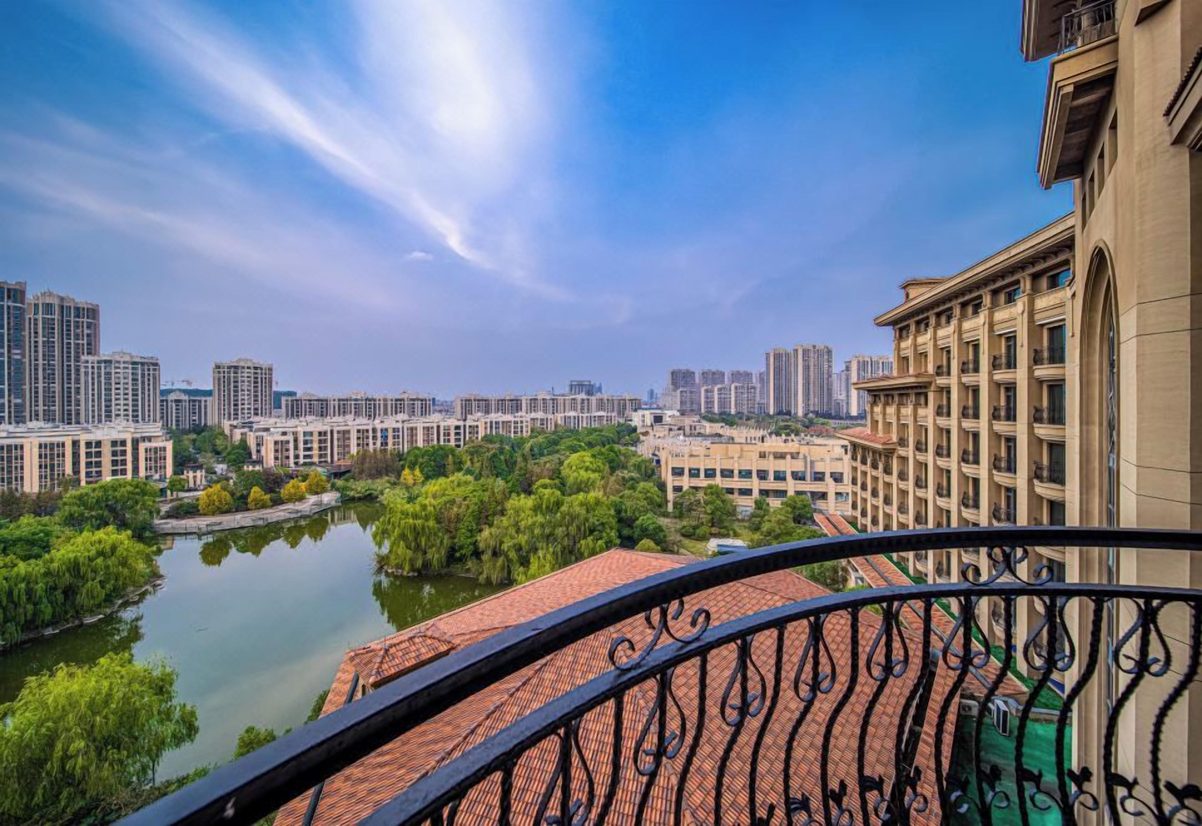 A balcony with a view of a river, buildings, and a clear sky.