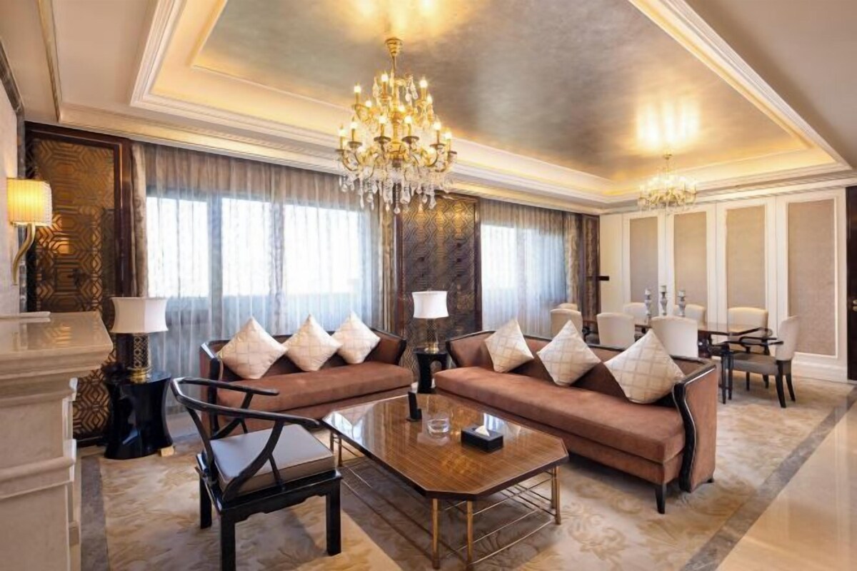 Un salon luxueux avec un grand canapé marron, une table basse et un lustre.
