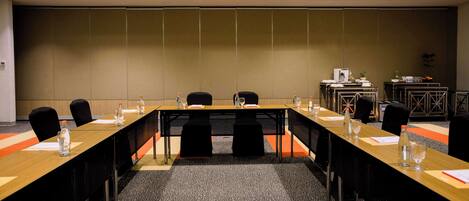 A conference room with a long table, black chairs, and a carpeted floor.