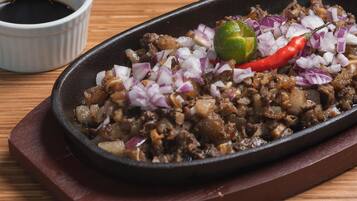 A dish with diced onions, a lime, and a red chili pepper on a black skillet.