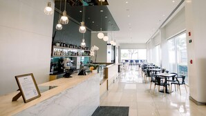 Un espace bar moderne avec des comptoirs en marbre, des luminaires suspendus et un présentoir à bouteilles bien en évidence.