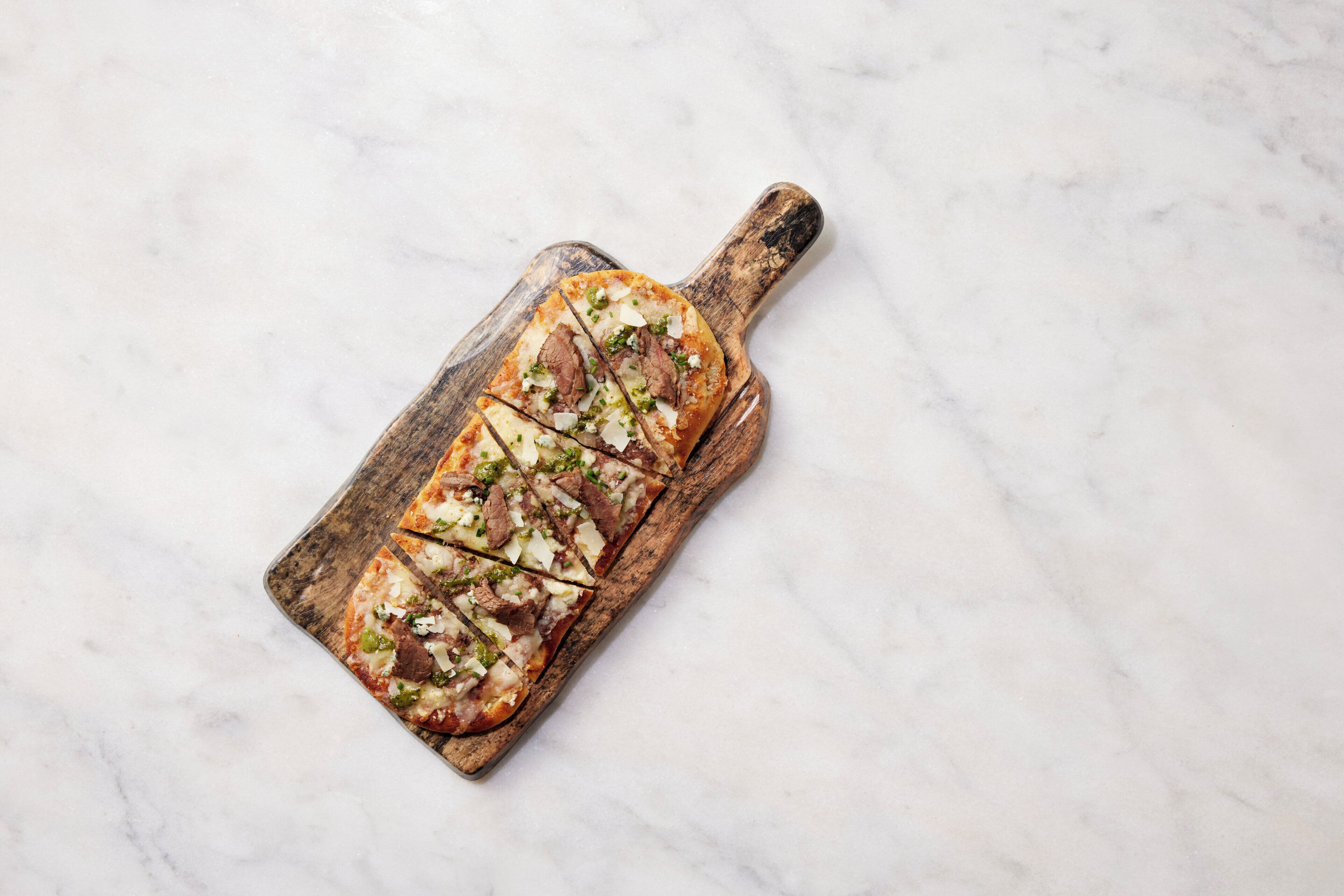 A pizza on a wooden cutting board.