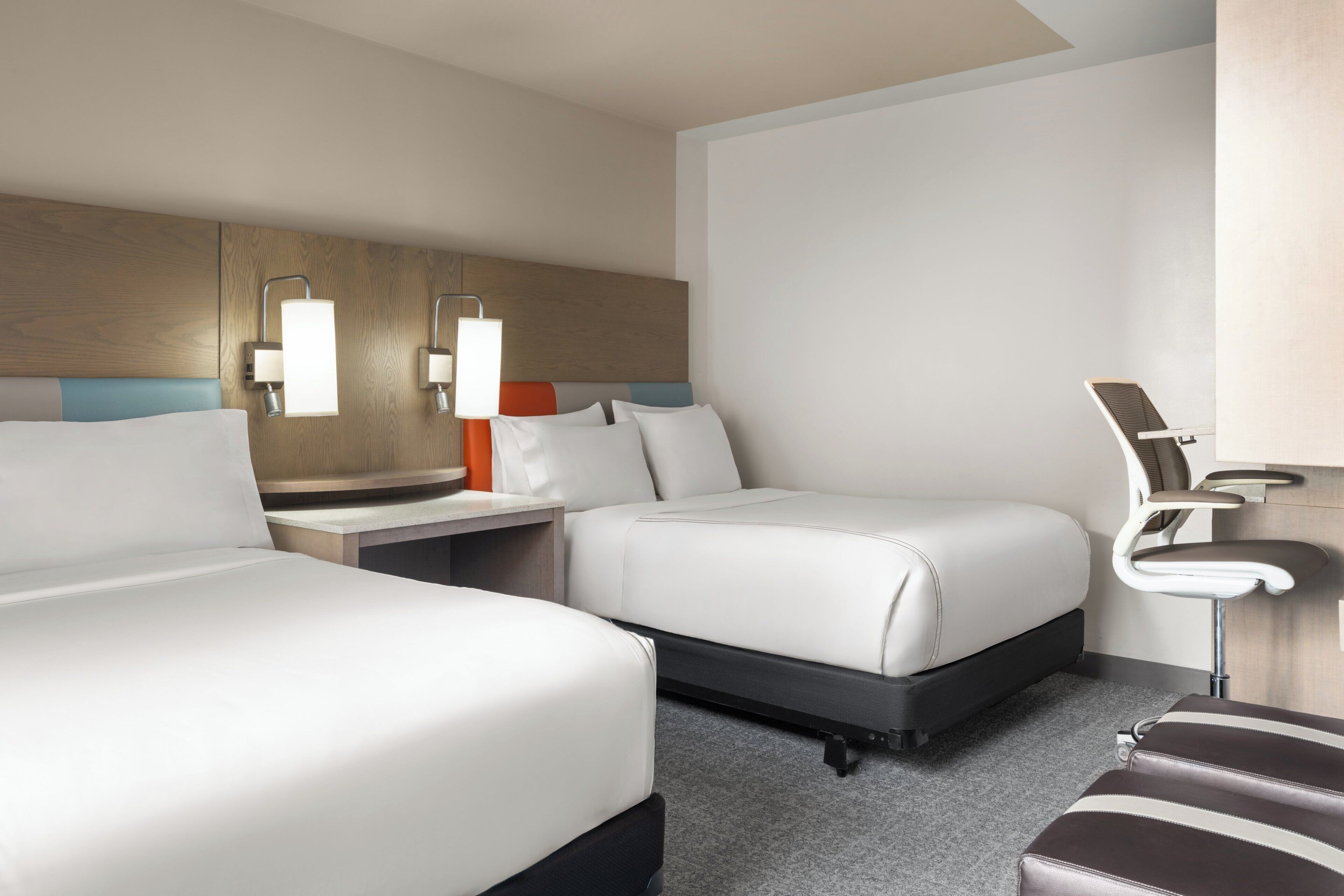 Een hotelkamer met twee bedden, een bureau, een stoel en een nachtkastje.