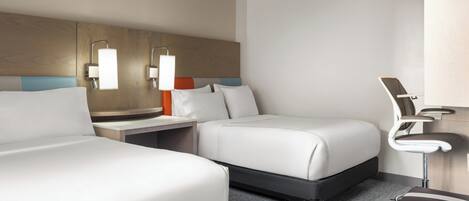 Een hotelkamer met twee bedden, een bureau, een stoel en een nachtkastje.