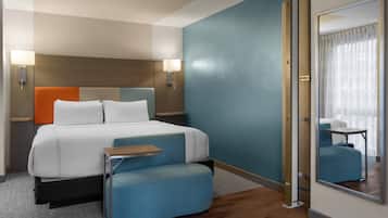 Une chambre d’hôtel avec un lit, des tables de chevet, un miroir et une vue sur un mur bleu.