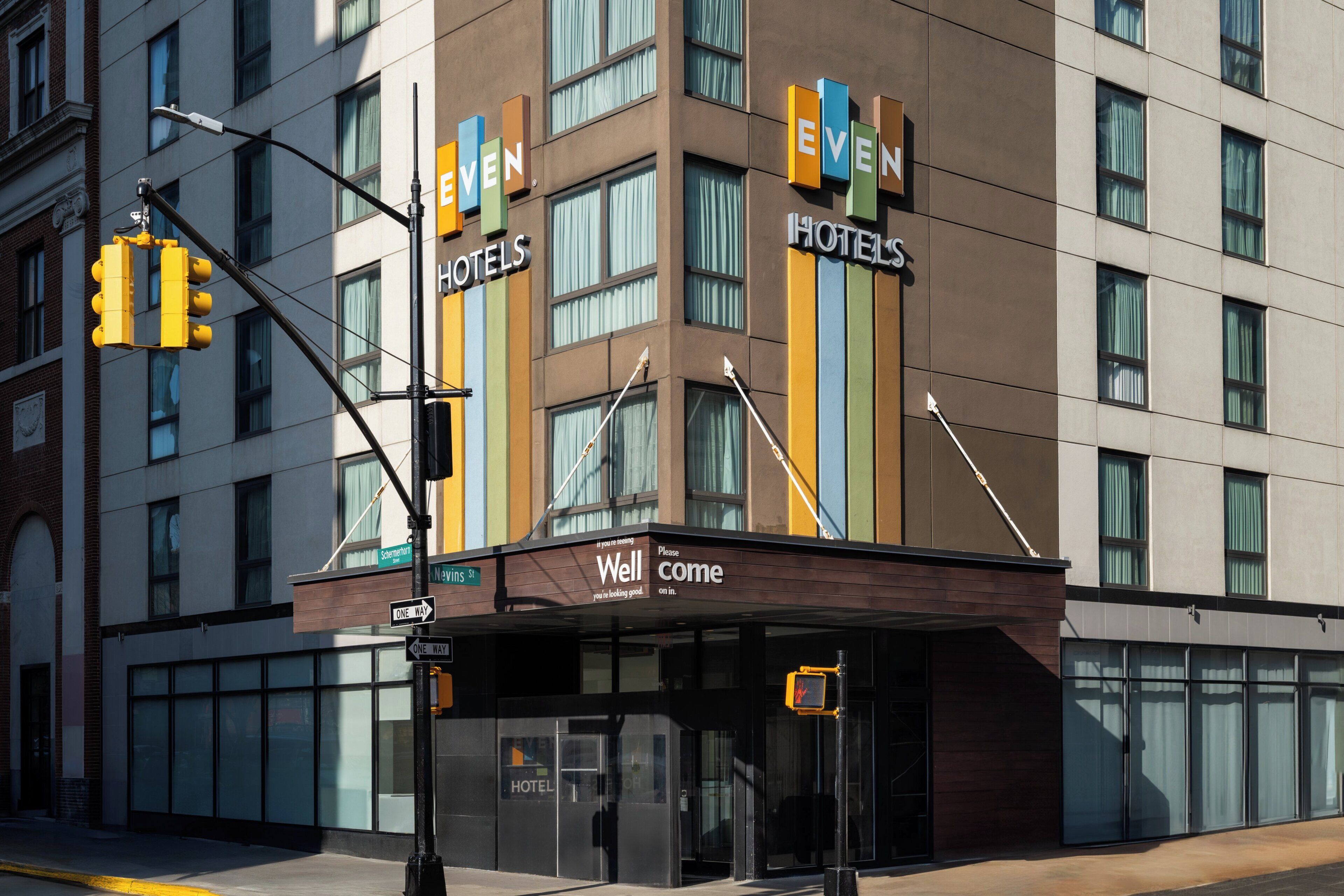 Ein Hotel mit moderner Fassade, großen Fenstern und einer auffälligen Beschilderung mit dem Schriftzug 'Even Hotels'.