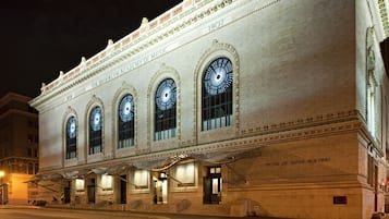 Un edificio histórico con ventanales arqueados y detalles ornamentales, identificado como la Academia de Música de Brooklyn.