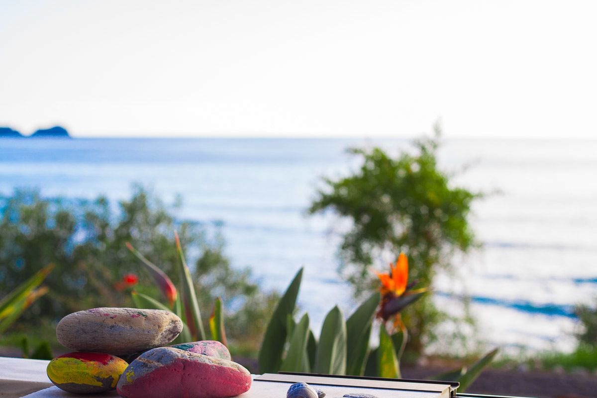 A serene outdoor setting with a view of the sea, featuring a table with stones and a book.