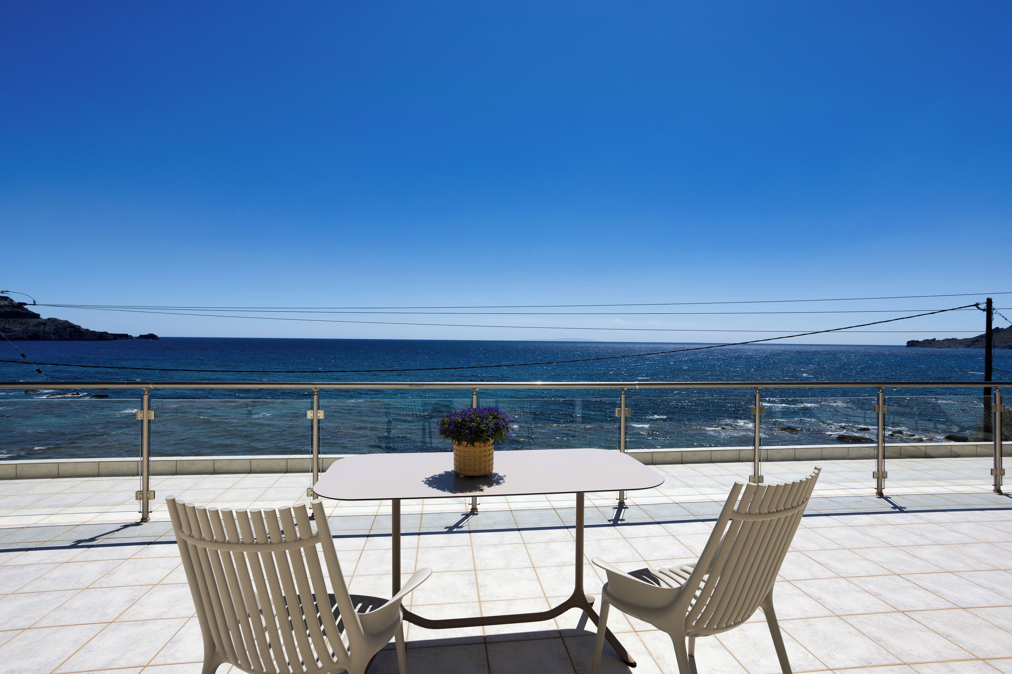 Een terras met een tafel en stoelen, met uitzicht op zee.