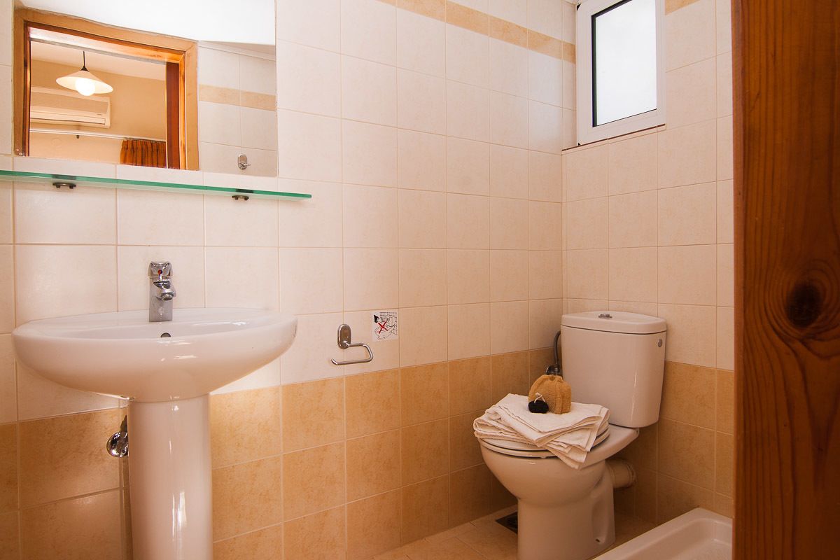 Une salle de bain avec un lavabo blanc, des toilettes et une étagère en verre au-dessus du lavabo.