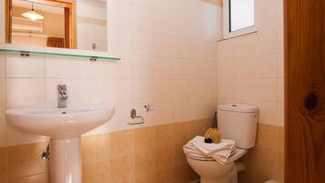 Une salle de bain avec un lavabo blanc, des toilettes et une étagère en verre au-dessus du lavabo.