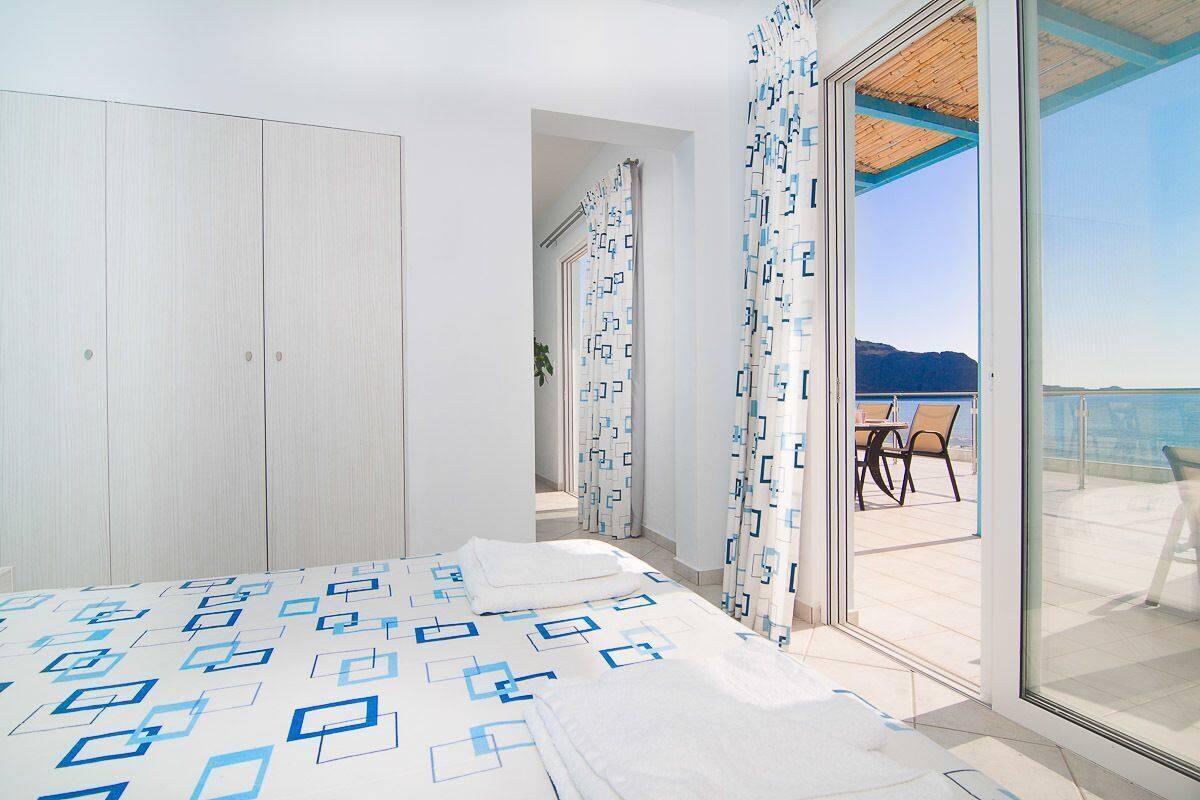A bedroom with a bed, a wardrobe, and a balcony with a view.
