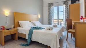 Ett hotellrum med två sängar, ett skrivbord, en stol, en TV och ett fönster med gardiner.