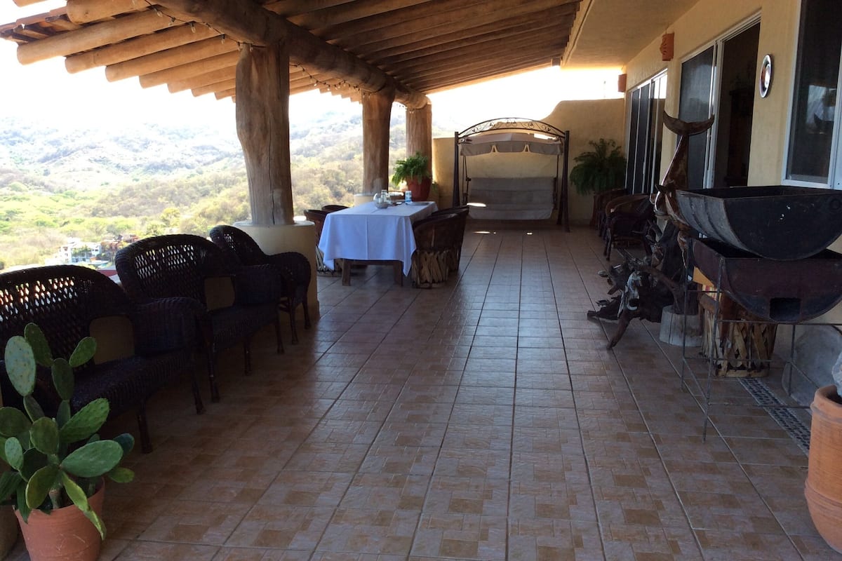 Une terrasse extérieure avec une table et des chaises, un barbecue et une vue sur les collines.