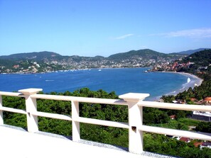 Un pueblo costero con vistas al mar, una barandilla blanca y abundante vegetación.