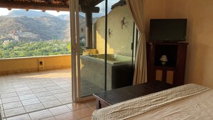 Une chambre d’hôtel avec un balcon, une baignoire, un lit et une télévision.