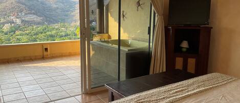 Ein Hotelzimmer mit Balkon, Badewanne, Bett und Fernseher.