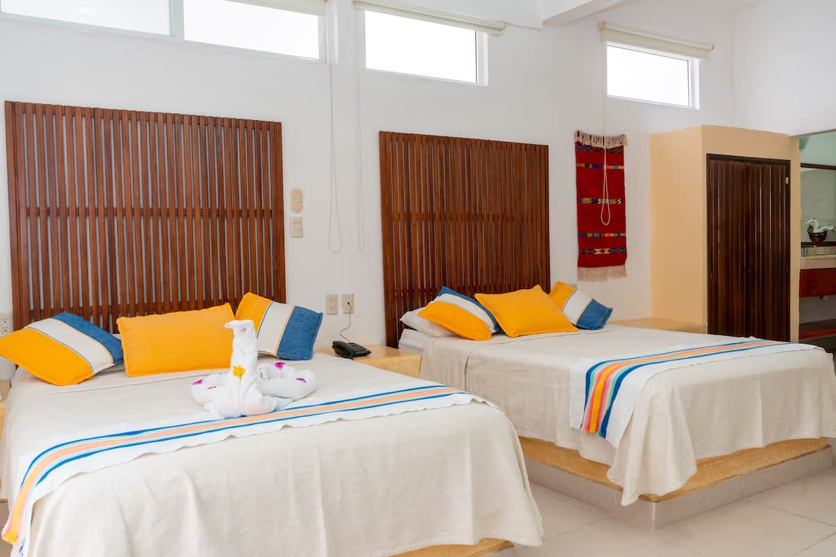 A hotel room with two beds, wooden headboards, and a red decorative wall hanging.