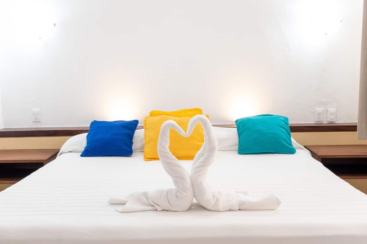 A hotel room with a bed, pillows, and a towel art arrangement.