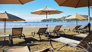 Un salon de plage doté de parasols et de chaises longues, le tout orienté vers l’océan.