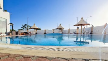 Una piscina al aire libre, sillones reclinables de piscina