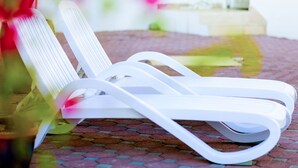 A white lounge chair with a cushion on a patterned floor.