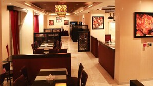A restaurant with booths and tables, a counter, and framed pictures on the walls.