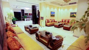 A spacious lobby with a large sofa set, a coffee table, and a potted plant.