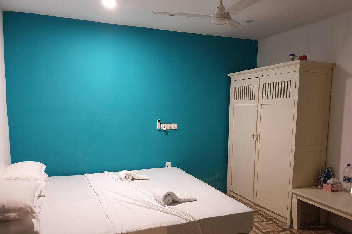 Ein Zimmer mit einem Bett, einem Kleiderschrank und einem Deckenventilator.