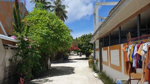 A narrow alleyway with a concrete path, a red bicycle, and a building with clothes hanging outside. - Beach Heaven Maldives - Golden Turtle Guest House (Huraa)
