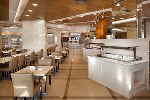 A modern restaurant with a long counter, multiple tables, and a buffet area. - Herbert Samuel Hod Dead Sea Hotel (Tamar)