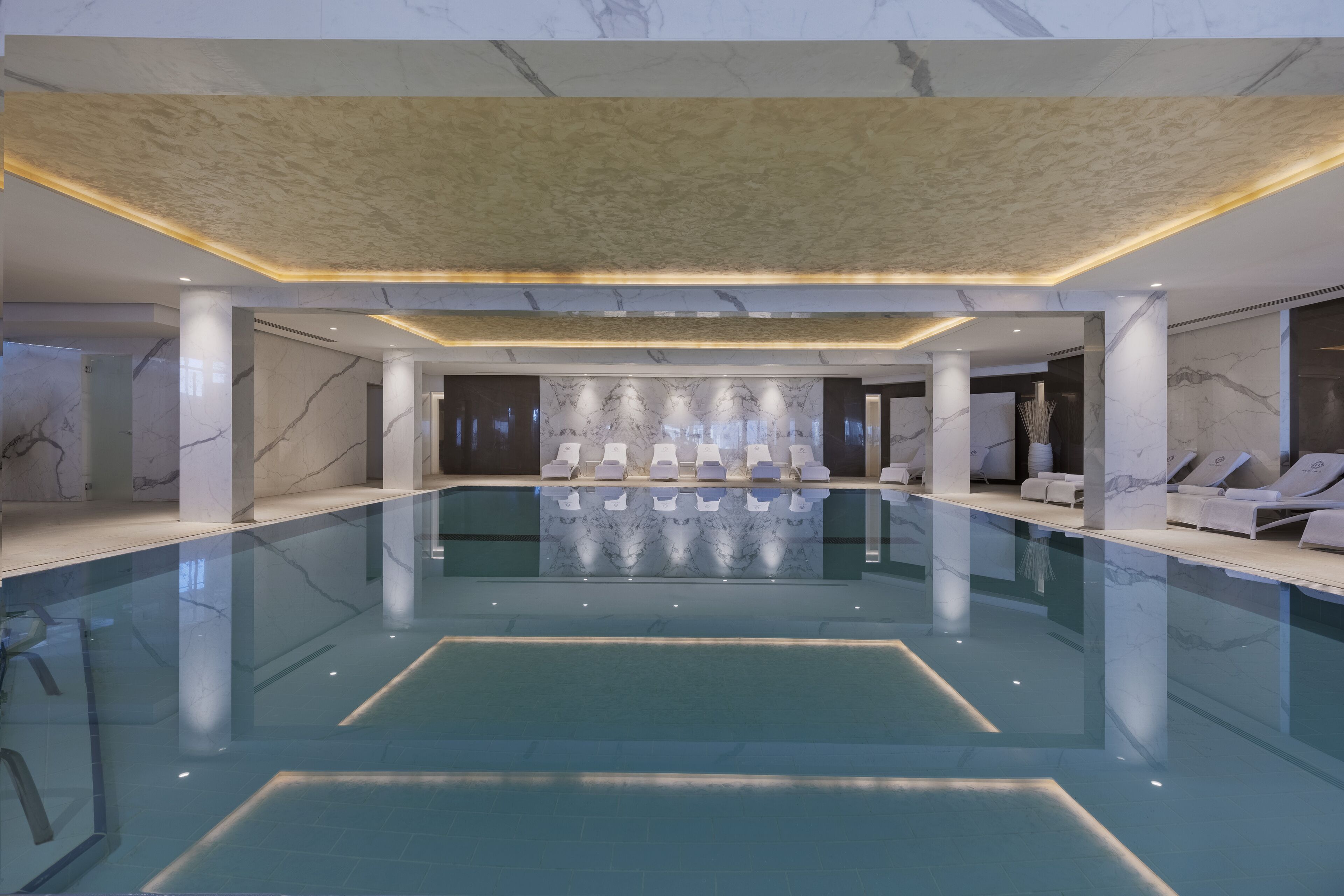 Una piscina techada, una piscina al aire libre, sombrillas