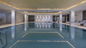 A spacious indoor swimming pool with marble walls and ceiling, surrounded by lounge chairs and a modern design. - Herbert Samuel Hod Dead Sea Hotel (Tamar)