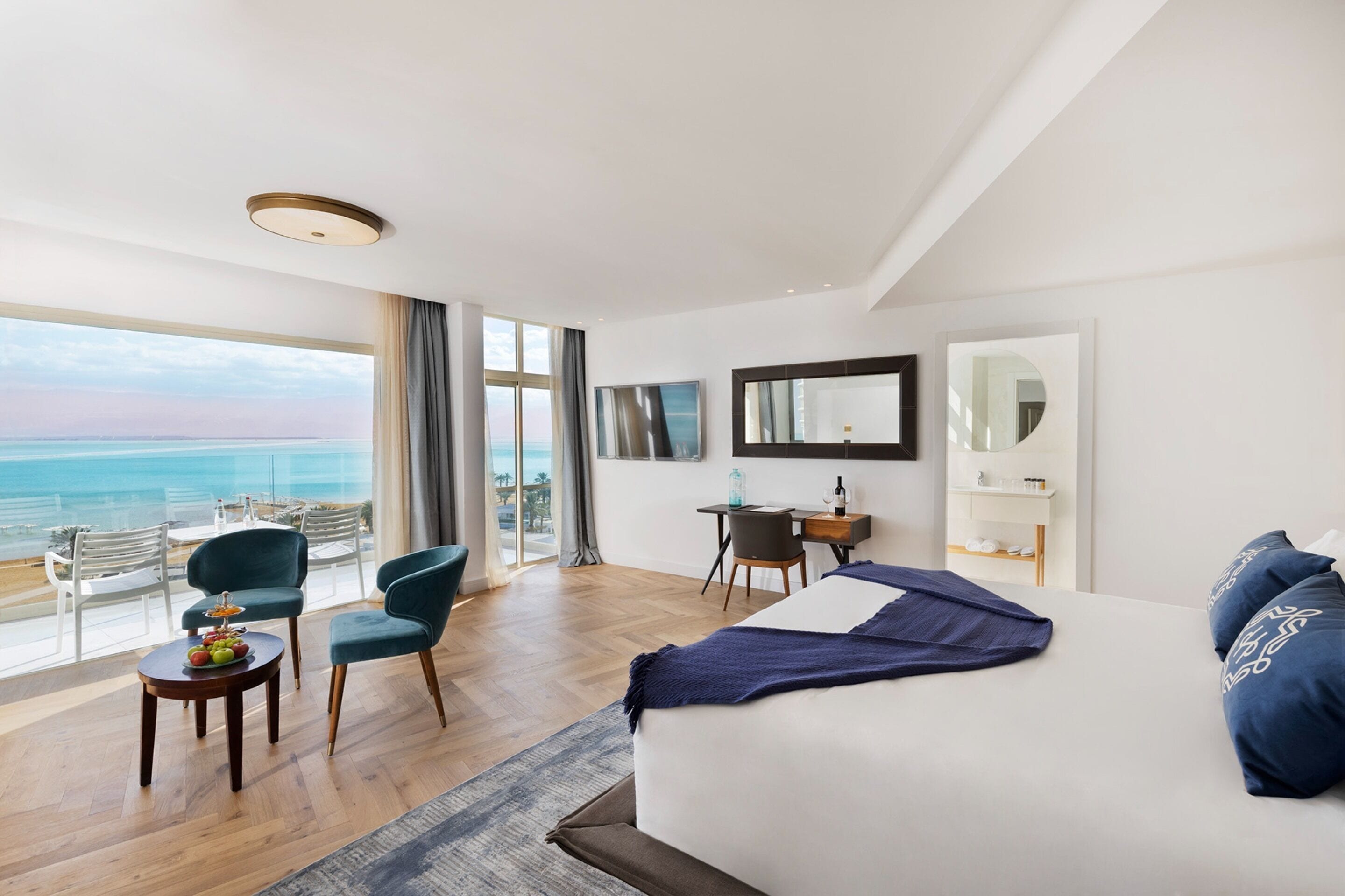 Habitación de hotel con una cama grande, un escritorio, una silla y vista al océano.